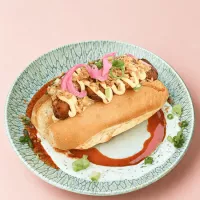 Hot dog au chorizo avec crème au cheddar rouge, oeufs brouillés et oignons.